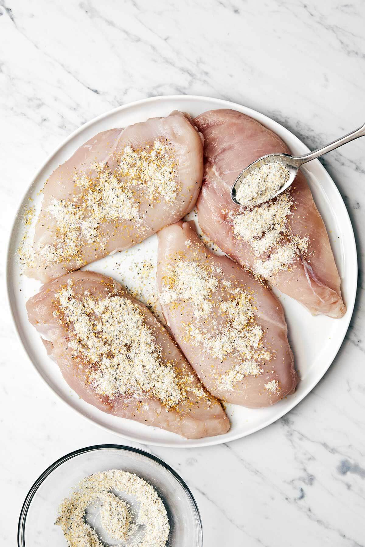 Adding lemon pepper seasoning to the chicken.