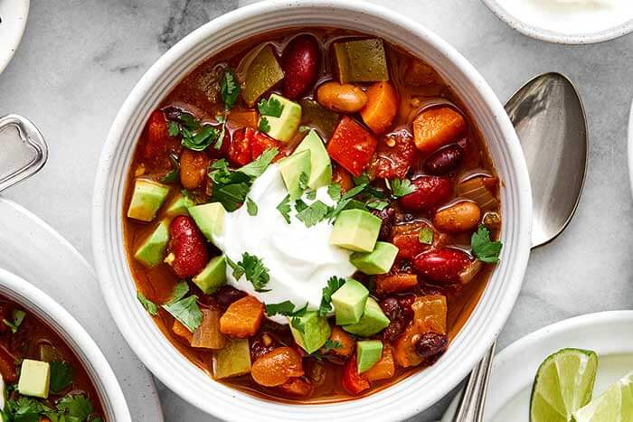 A bowl of vegetarian chili with avocado.