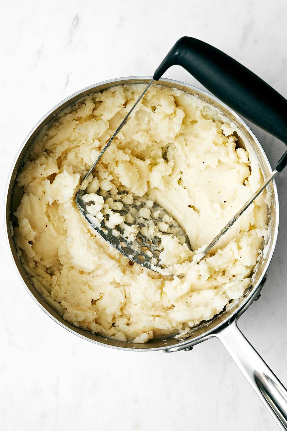 Mashing potatoes in a pot.