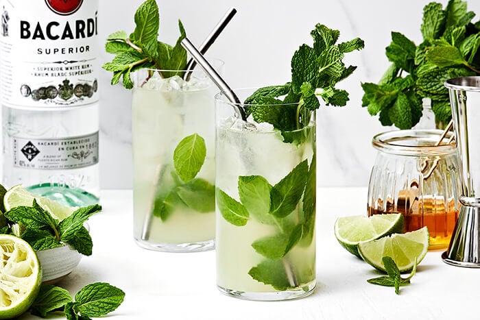 Two mojito cocktails on a table.