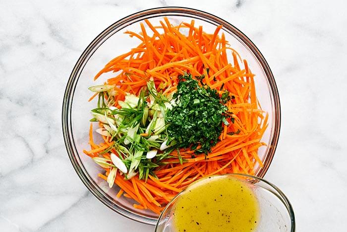Pouring a dressing into a carrot salad.