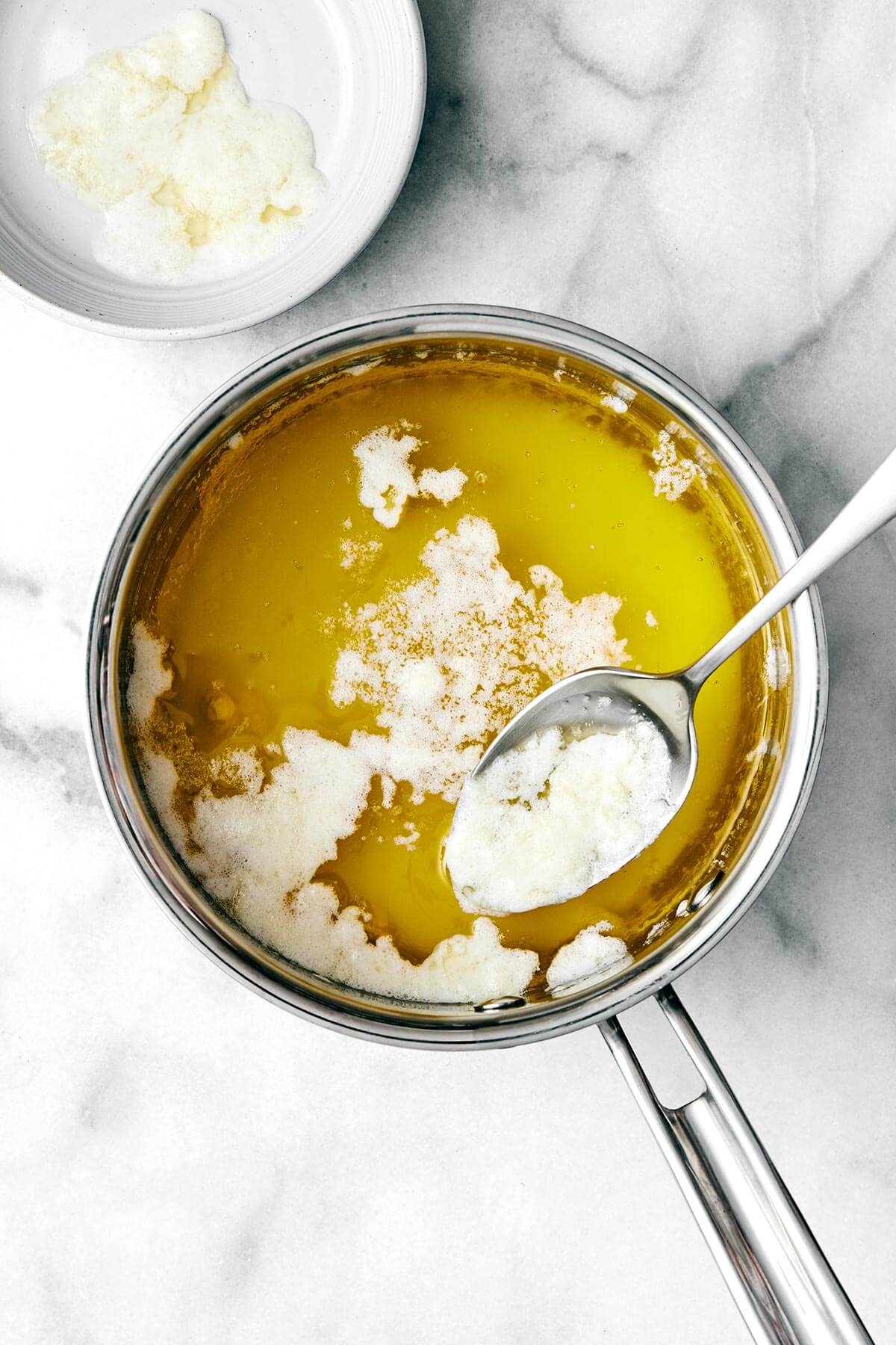 Homemade ghee (clarified butter) is incredibly easy to make, much cheaper than store-bought versions, and is perfect for those who are dairy-sensitive. Boiling butter in a pot.