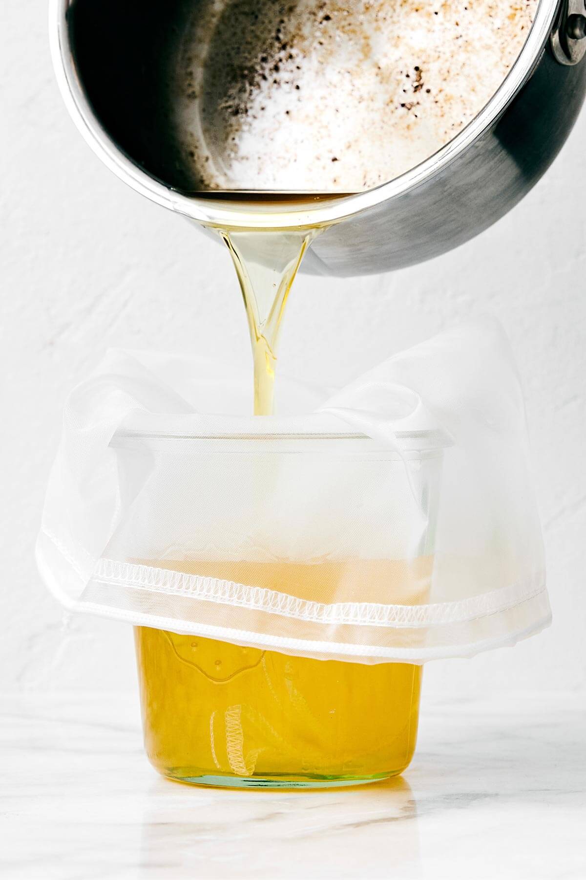Homemade ghee (clarified butter) is incredibly easy to make, much cheaper than store-bought versions, and is perfect for those who are dairy-sensitive. Straining ghee in a cup.
