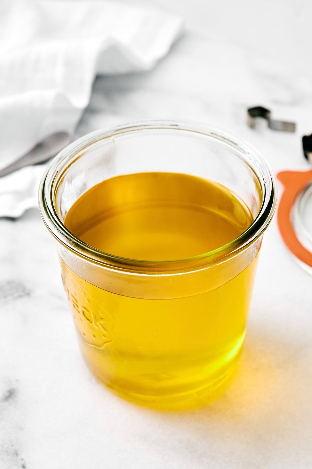 Homemade ghee (clarified butter) is incredibly easy to make, much cheaper than store-bought versions, and is perfect for those who are dairy-sensitive. Liquid ghee in a glass jar.