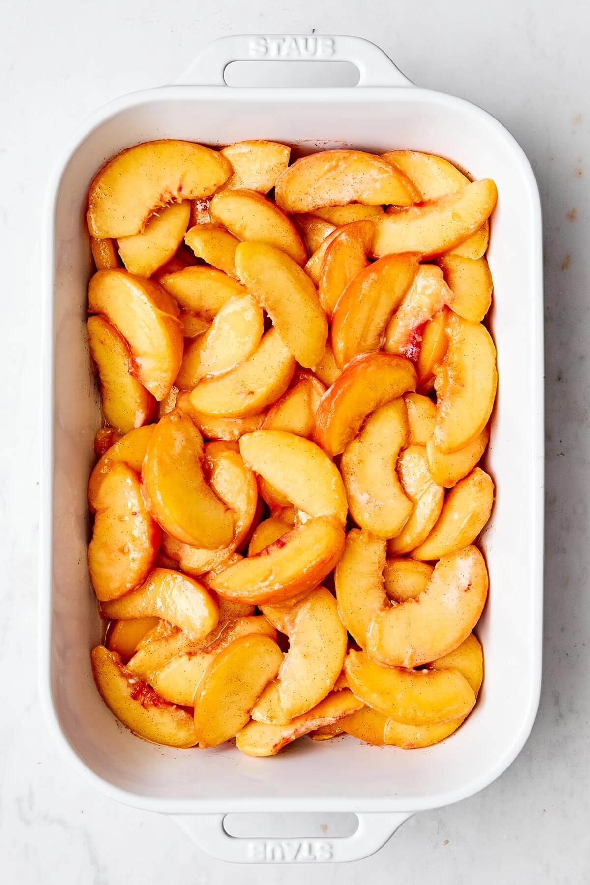 This peach crisp dessert with a crumble oatmeal topping is the best way to celebrate summer peach season! Plus, it's completely gluten-free. Peach filling in a casserole dish.