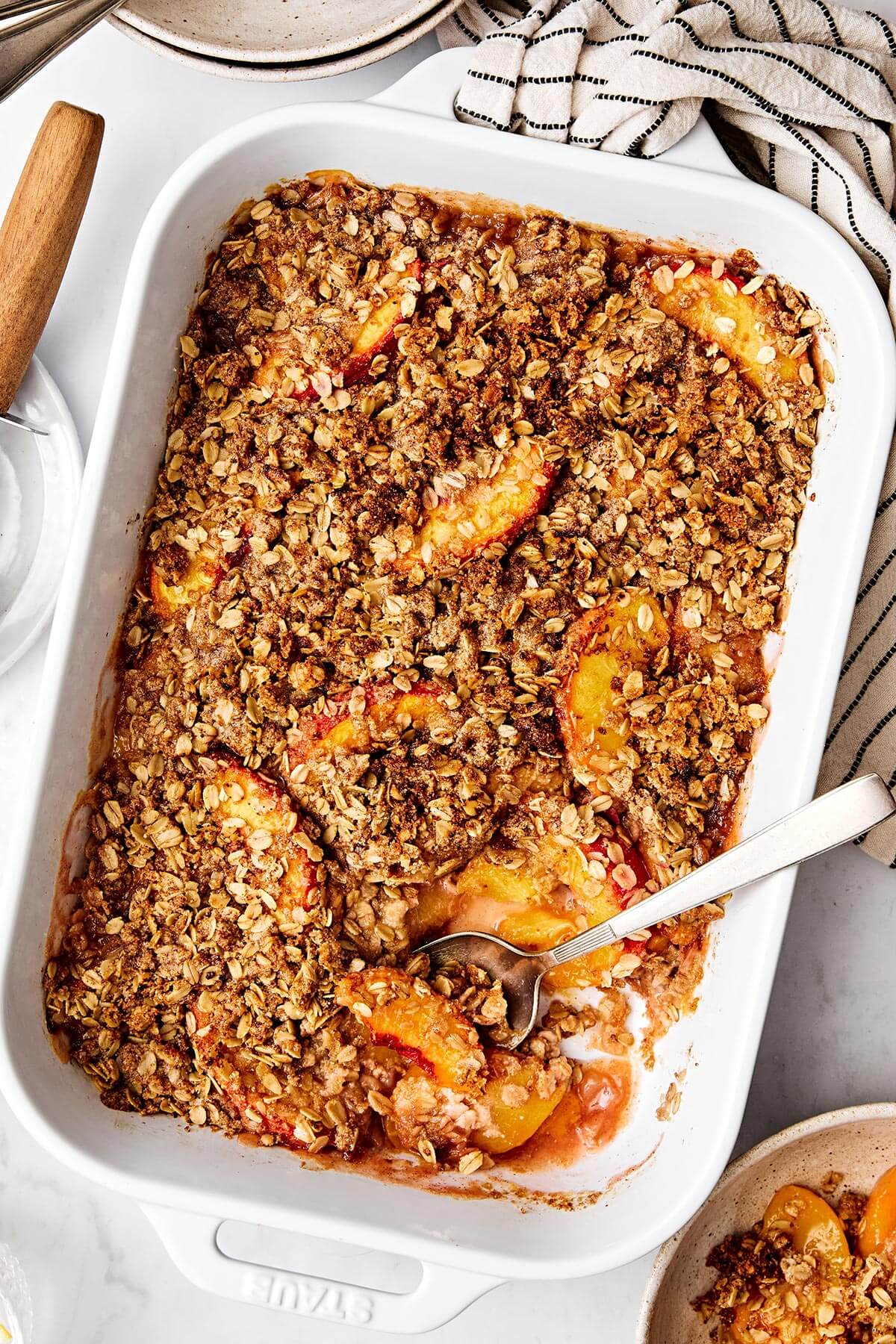 This peach crisp dessert with a crumble oatmeal topping is the best way to celebrate summer peach season! Plus, it's completely gluten-free. Baked peach crisp in a casserole dish.