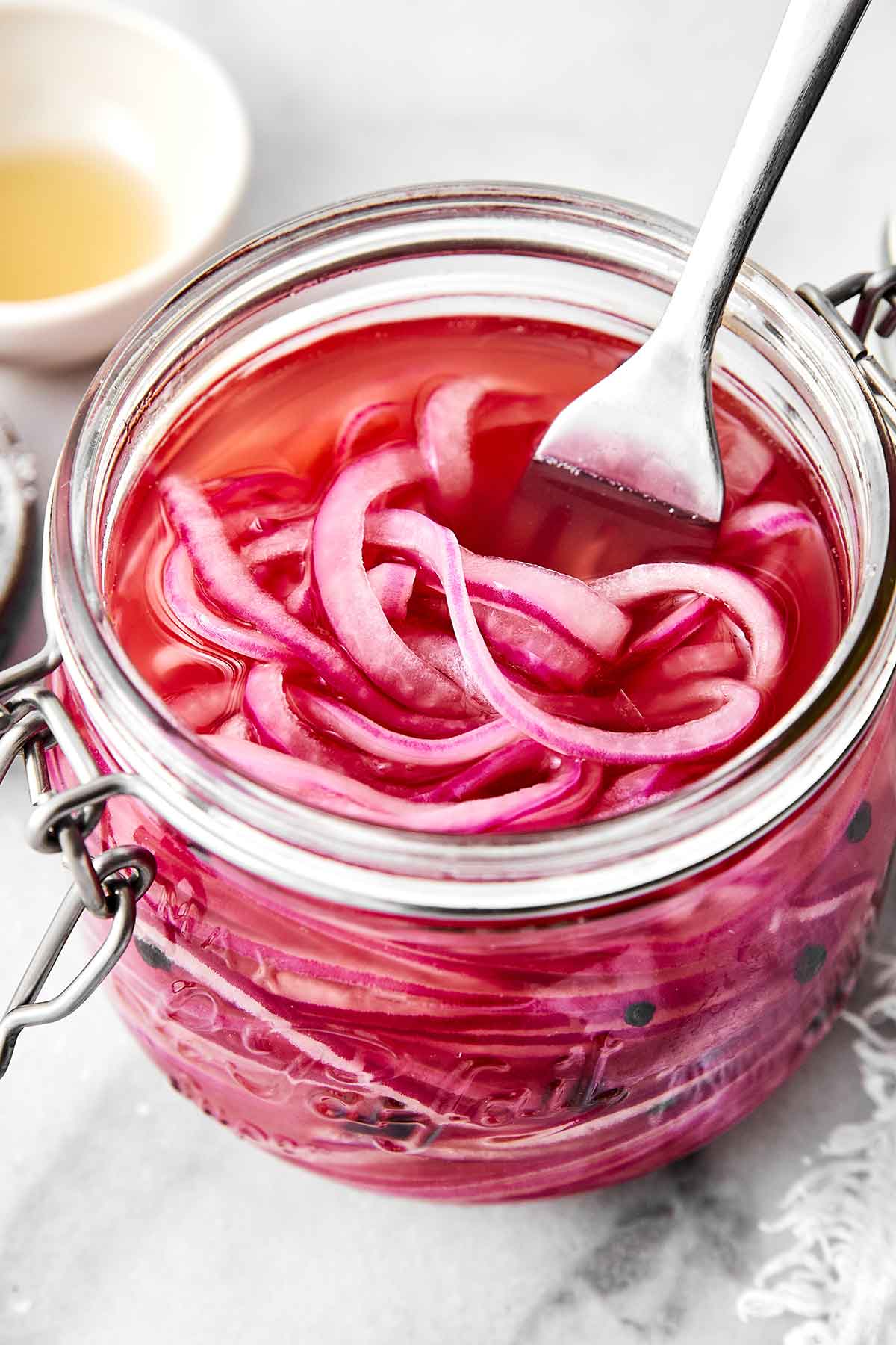 A glass jar of quick pickled red onions.