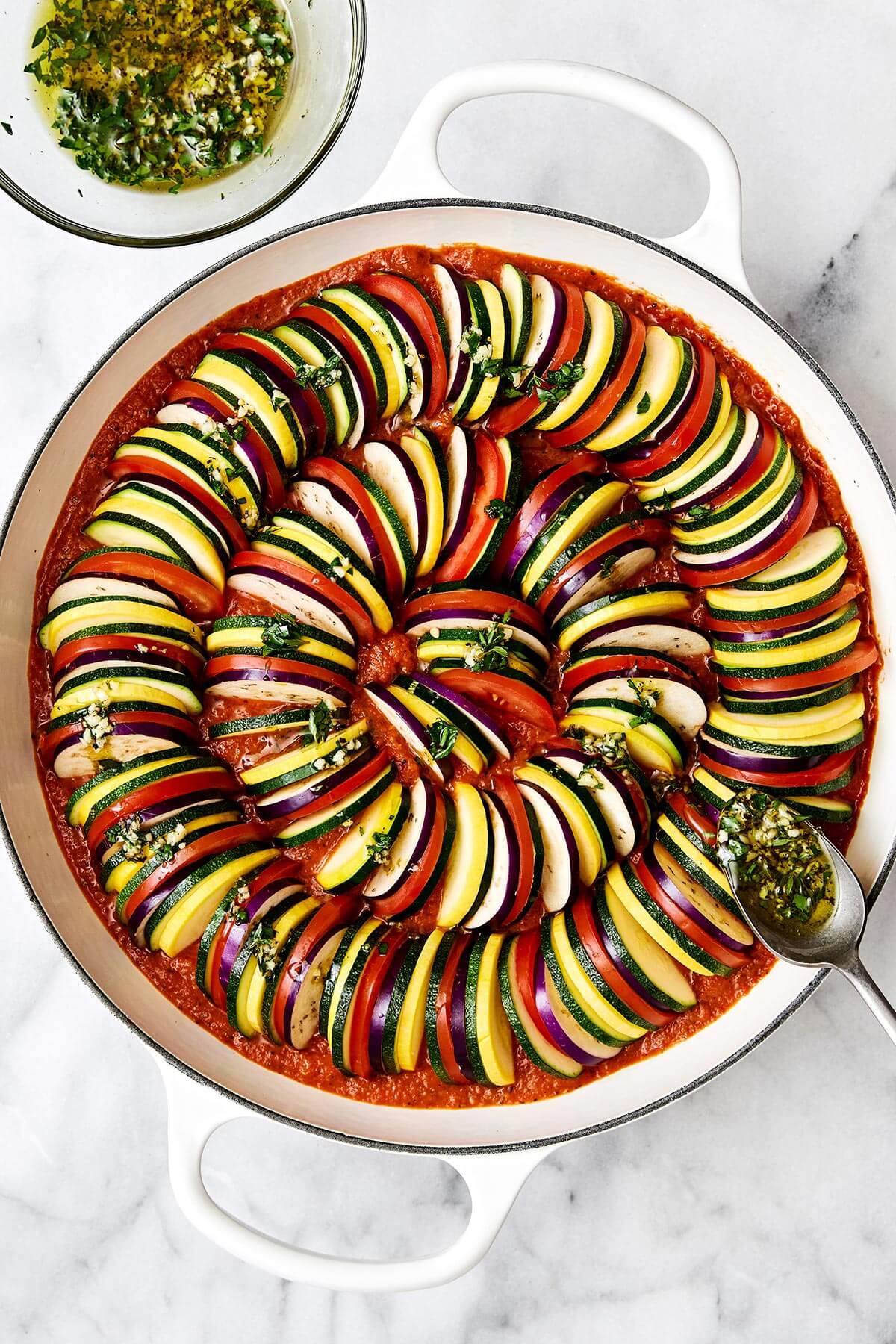 Pouring sauce over ratatouille before baking.