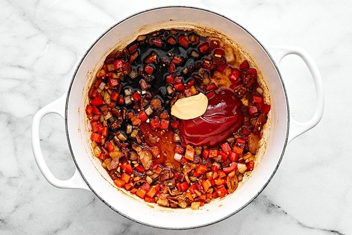 Mixing baked beans and aromatics in a pot.