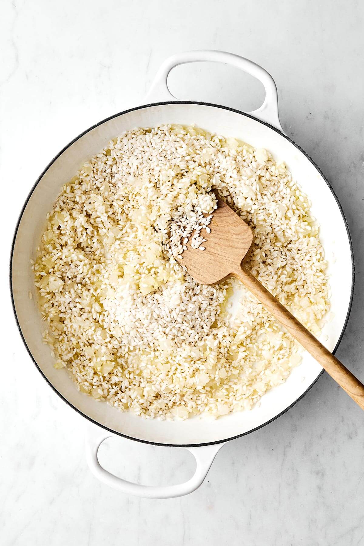 This broccoli parmesan risotto turns an Italian comfort food classic into a rich and creamy veggie delight layered with broccoli rice, fresh parmesan cheese, parsley, and butter. I love to enjoy a bowl of this with extra cheese on top, but it's also always a hit for holiday dinners. Cooking rice in a pan.