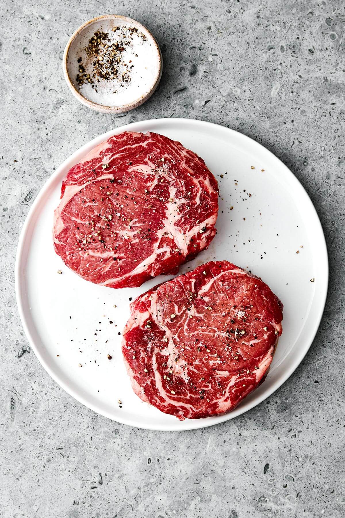 Seasoning ribeye steaks.