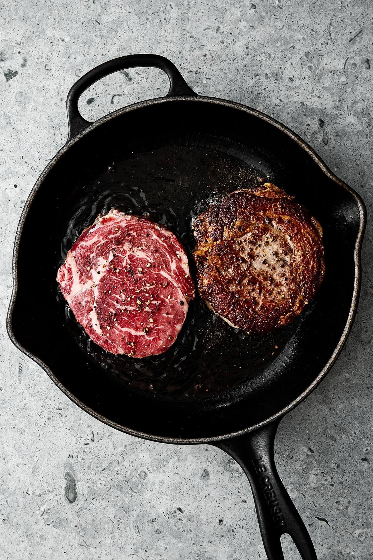 Cooking ribeye steak in a cast iron pan.