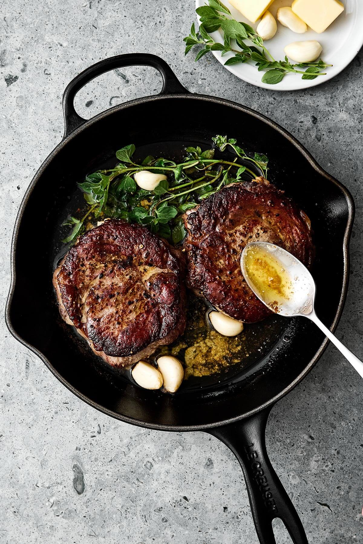 Searing ribeye steak in a cast iron pan.