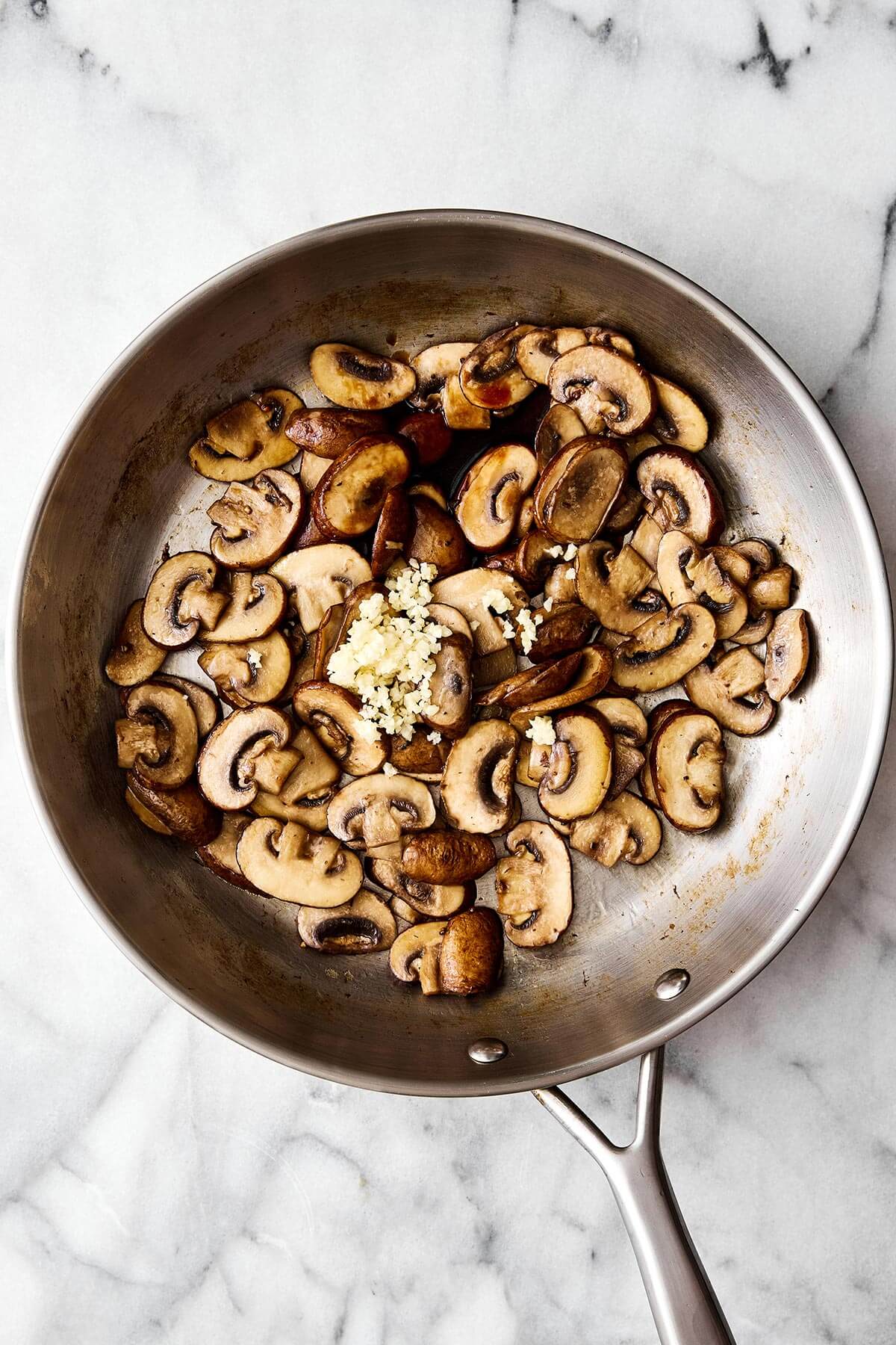 Sautéed mushrooms are the simplest way to add a buttery umami flavor to any meal — especially with steak, burgers, and more! Cooking mushrooms with garlic in a pan.