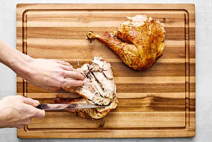 Step four of how to carve a turkey: separate the drumstick.