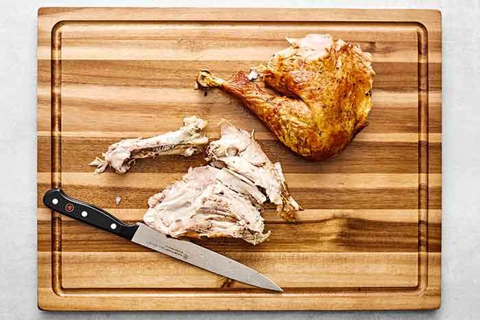 Step five of how to carve a turkey: remove the bone from the thigh.