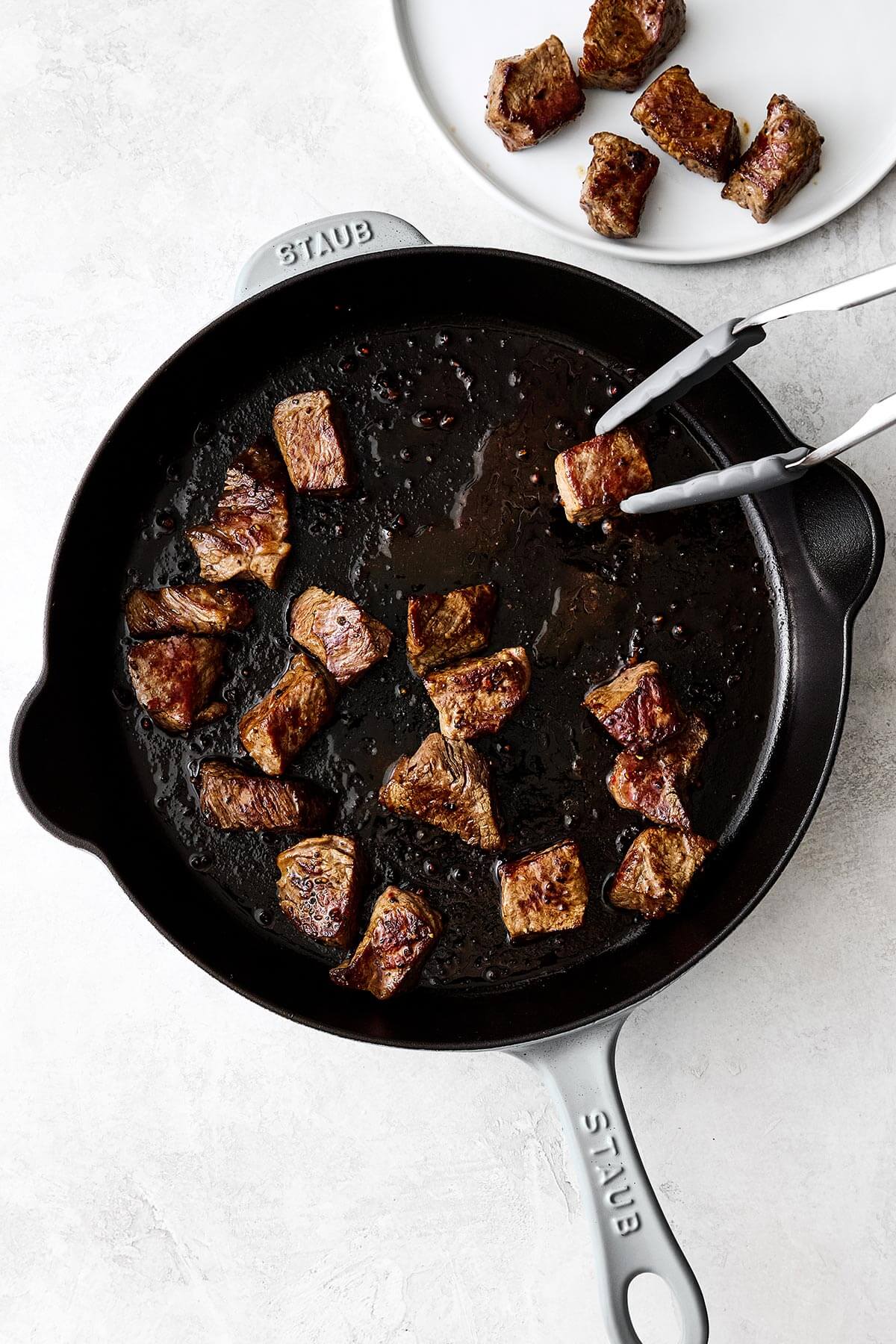 Cooking garlic butter steak bites in a skillet.