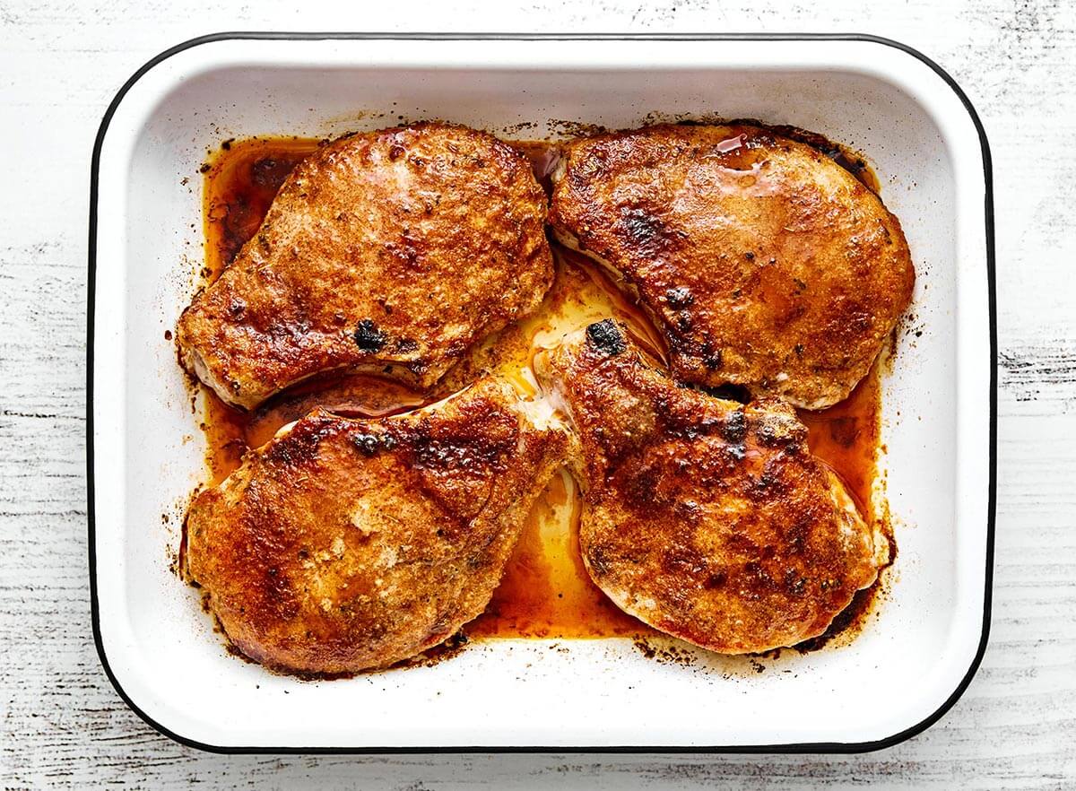 These baked pork chops are the best dinner made in less than 30 minutes! They're tender and juicy, with a smoky-sweet caramelized flavor. Baked pork chops in a whit baking dish.