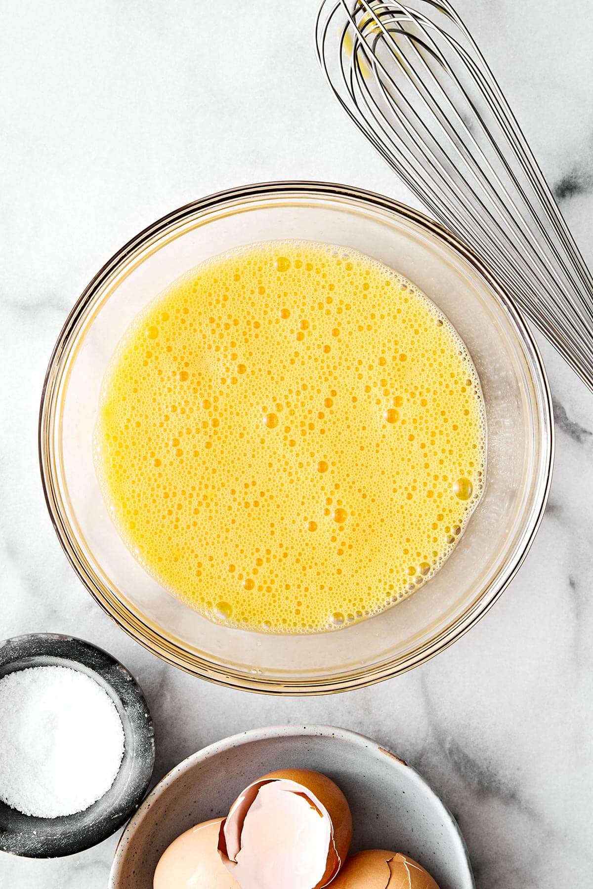 Learn how to make scrambled eggs with my easy, foolproof method! Your eggs will turn out silky and creamy every single time. A bowl of whisked eggs.
