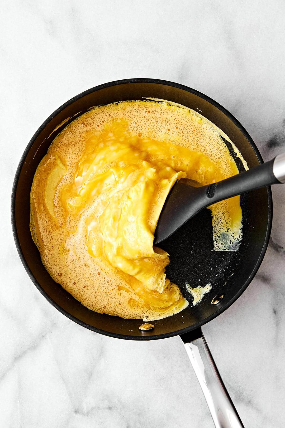 Learn how to make scrambled eggs with my easy, foolproof method! Your eggs will turn out silky and creamy every single time. Folding scrambled eggs in a pan.
