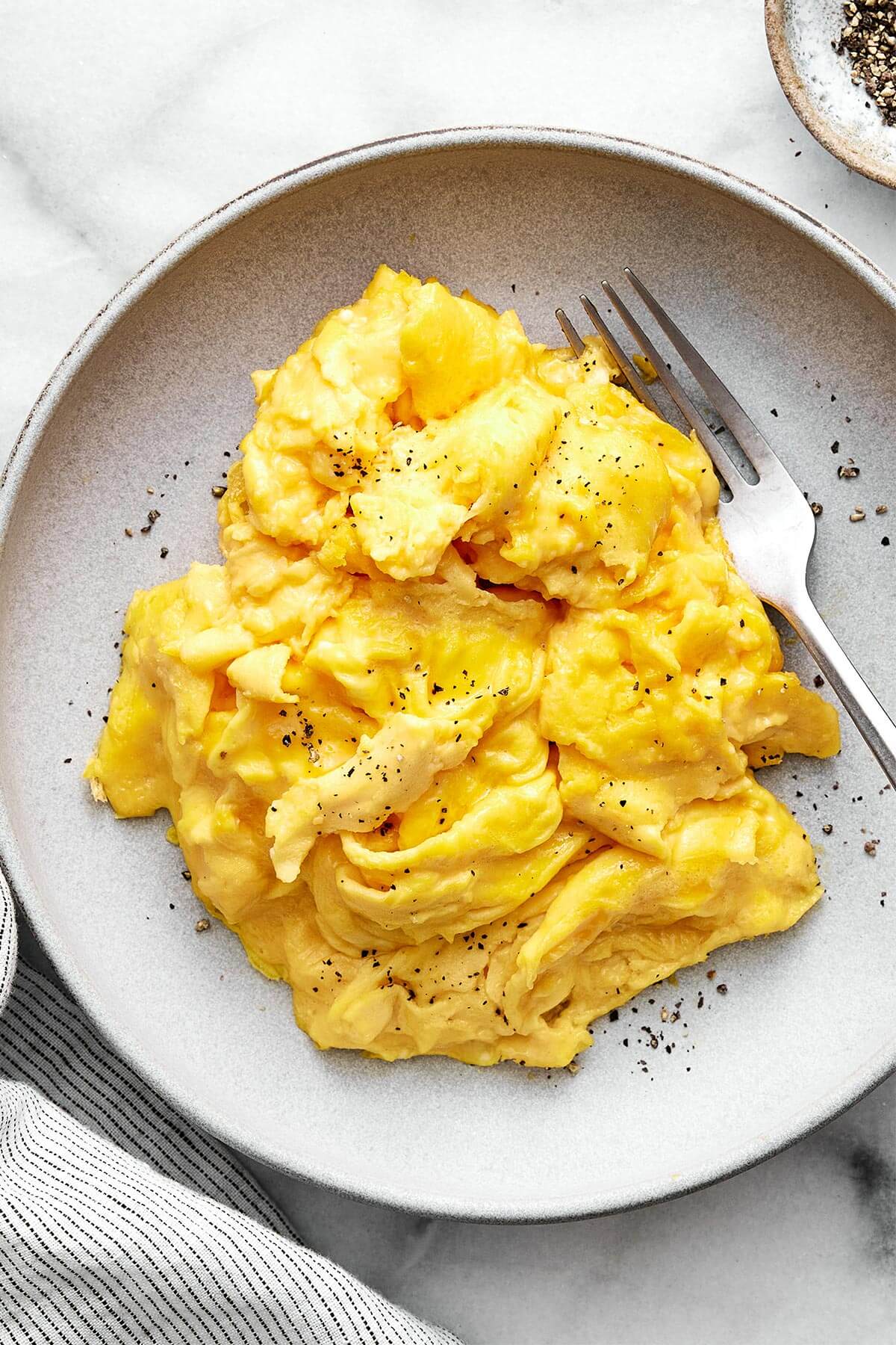 Learn how to make scrambled eggs with my easy, foolproof method! Your eggs will turn out silky and creamy every single time. A plate of scrambled eggs.