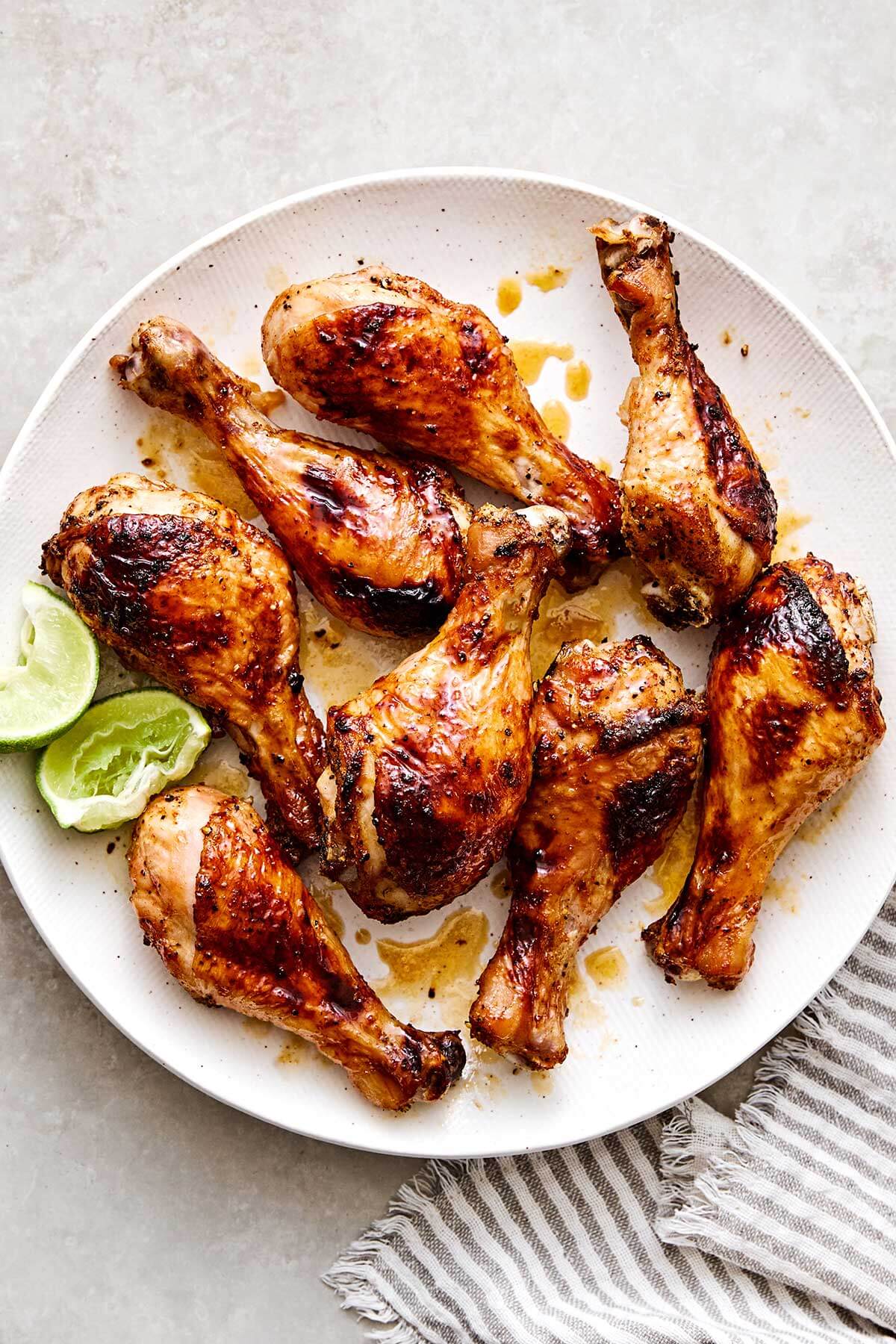 Hot honey chicken drumsticks with limes on a plate.