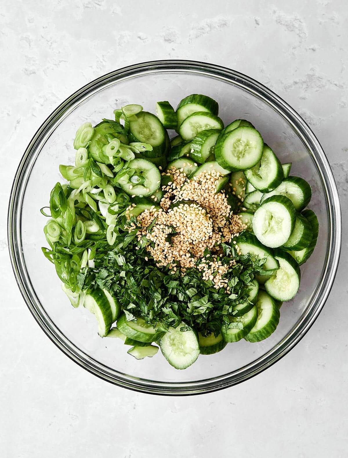 Fresh, crunchy, and packed with flavor, this Asian cucumber salad is the perfect side dish for Asian-inspired dinners! Mixing Asian cucumber salad in a bowl.