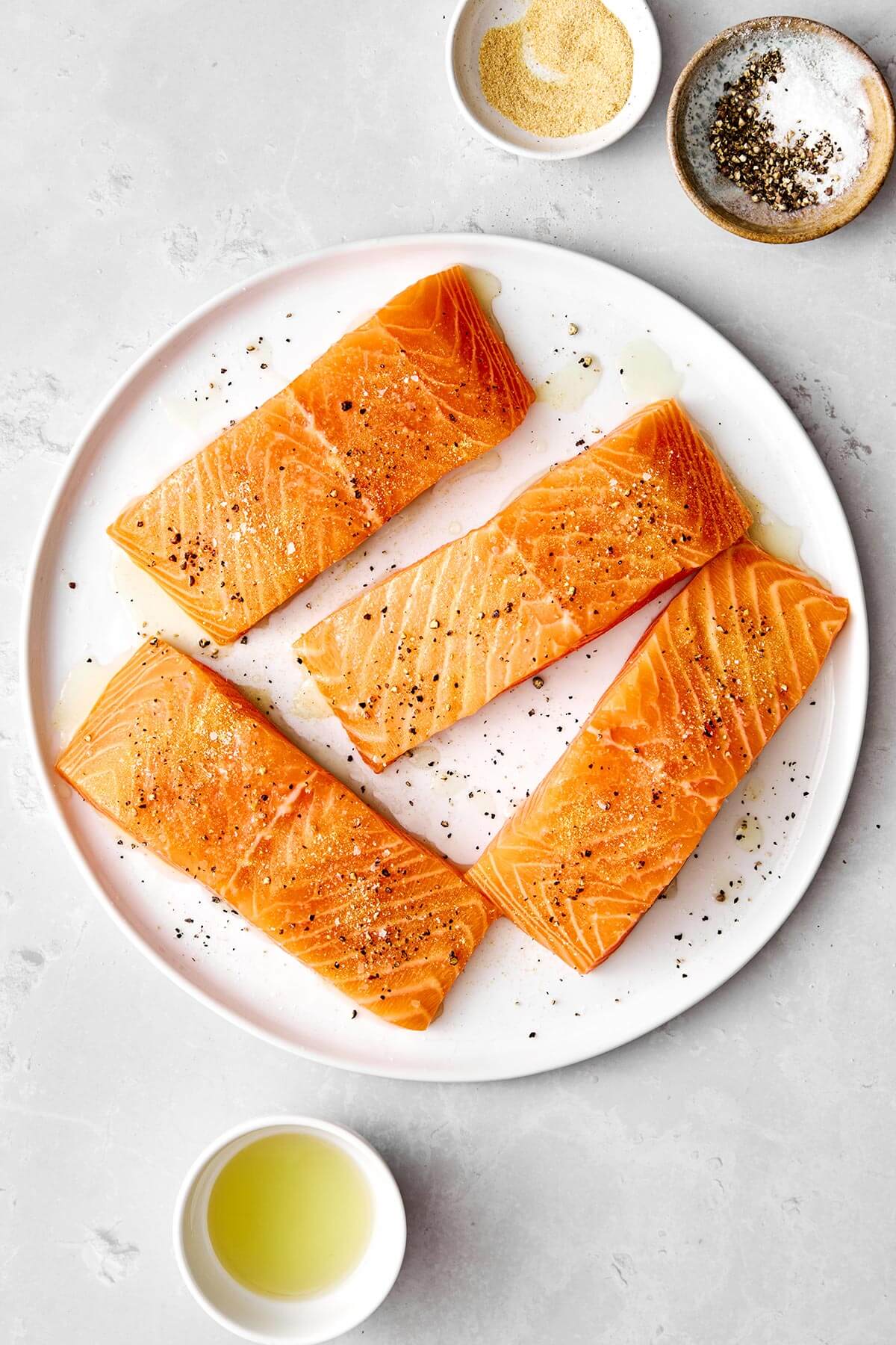 Seasoning salmon fillets before grilling.