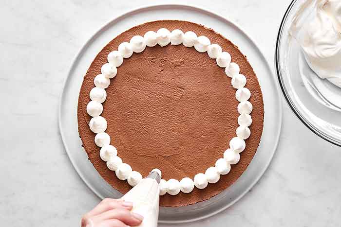 Adding whipped cream on cake.