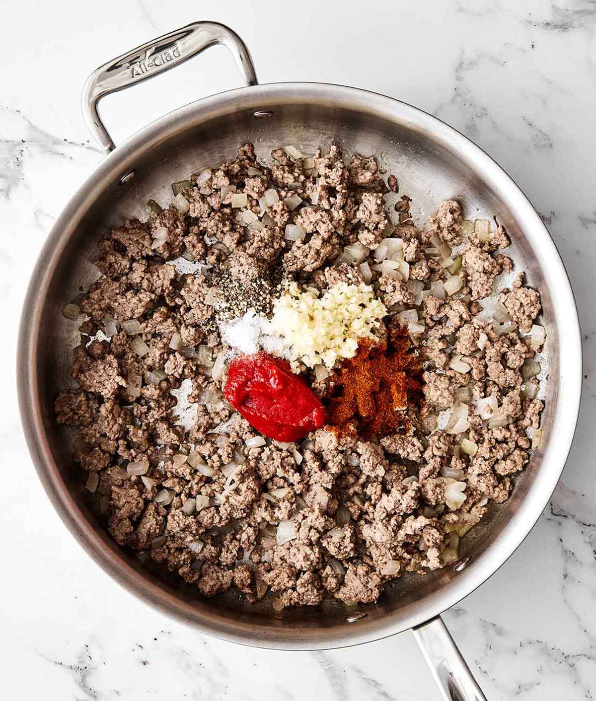 Adding aromatics to ground beef.