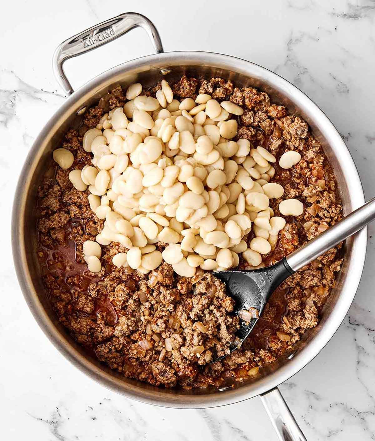 Adding butter beans to ground beef.