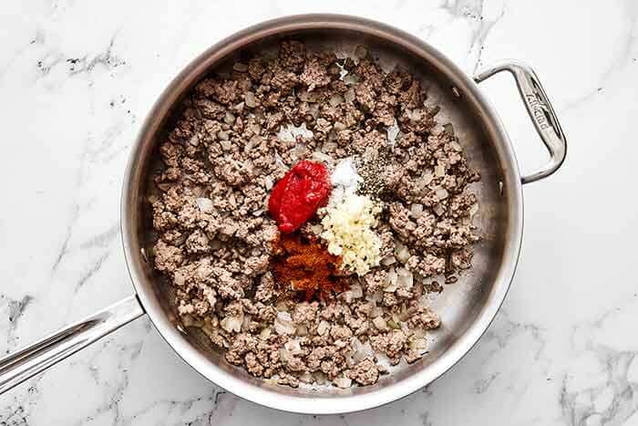 Adding spices to ground beef.