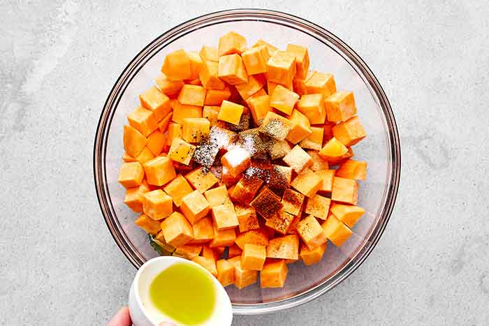Tossing sweet potatoes in seasoning before roasting.