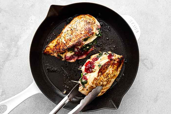 Searing cranberry stuffed chicken breasts.