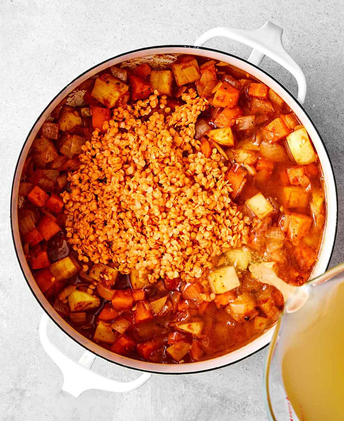 Step three of red lentil soup: add broth and lentils.