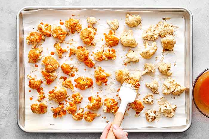 Step four of buffalo cauliflower: brush the sauce.