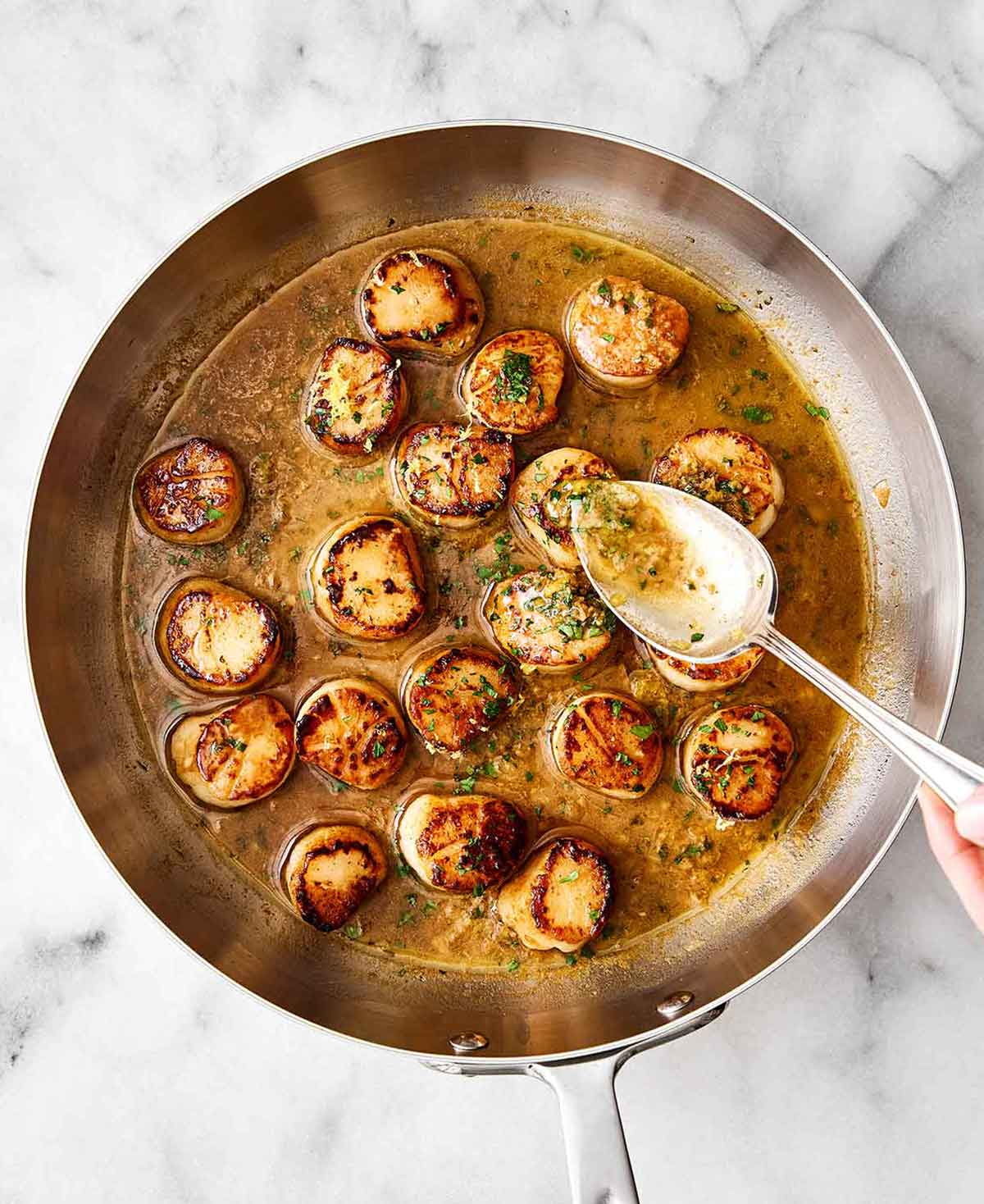 Step four of seared scallops: pour sauce over scallops.