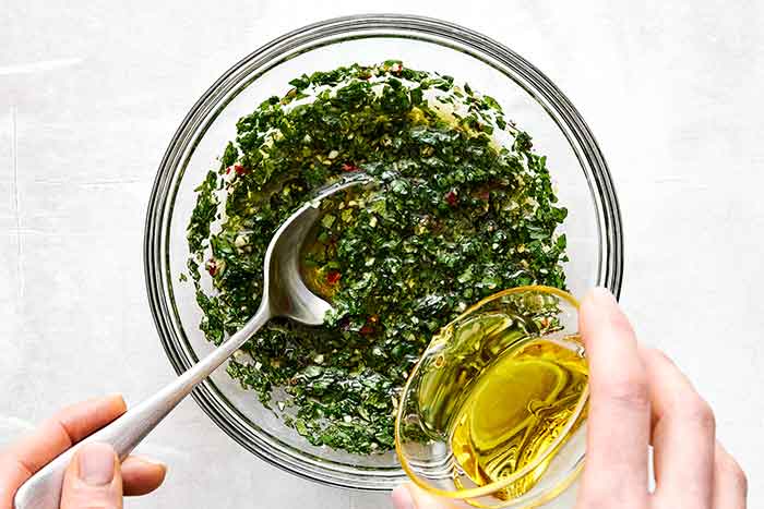Step three of mint chimichurri: add olive oil.