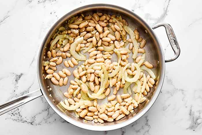 Step two of spinach and white bean salad: add the beans.