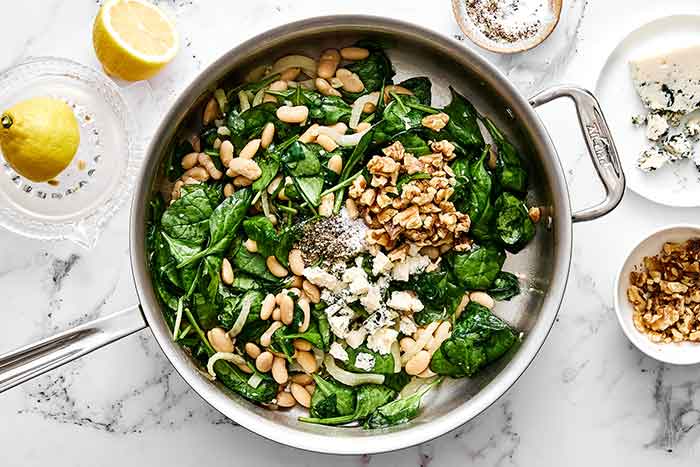 Step four of spinach and white bean salad: add the spinach.