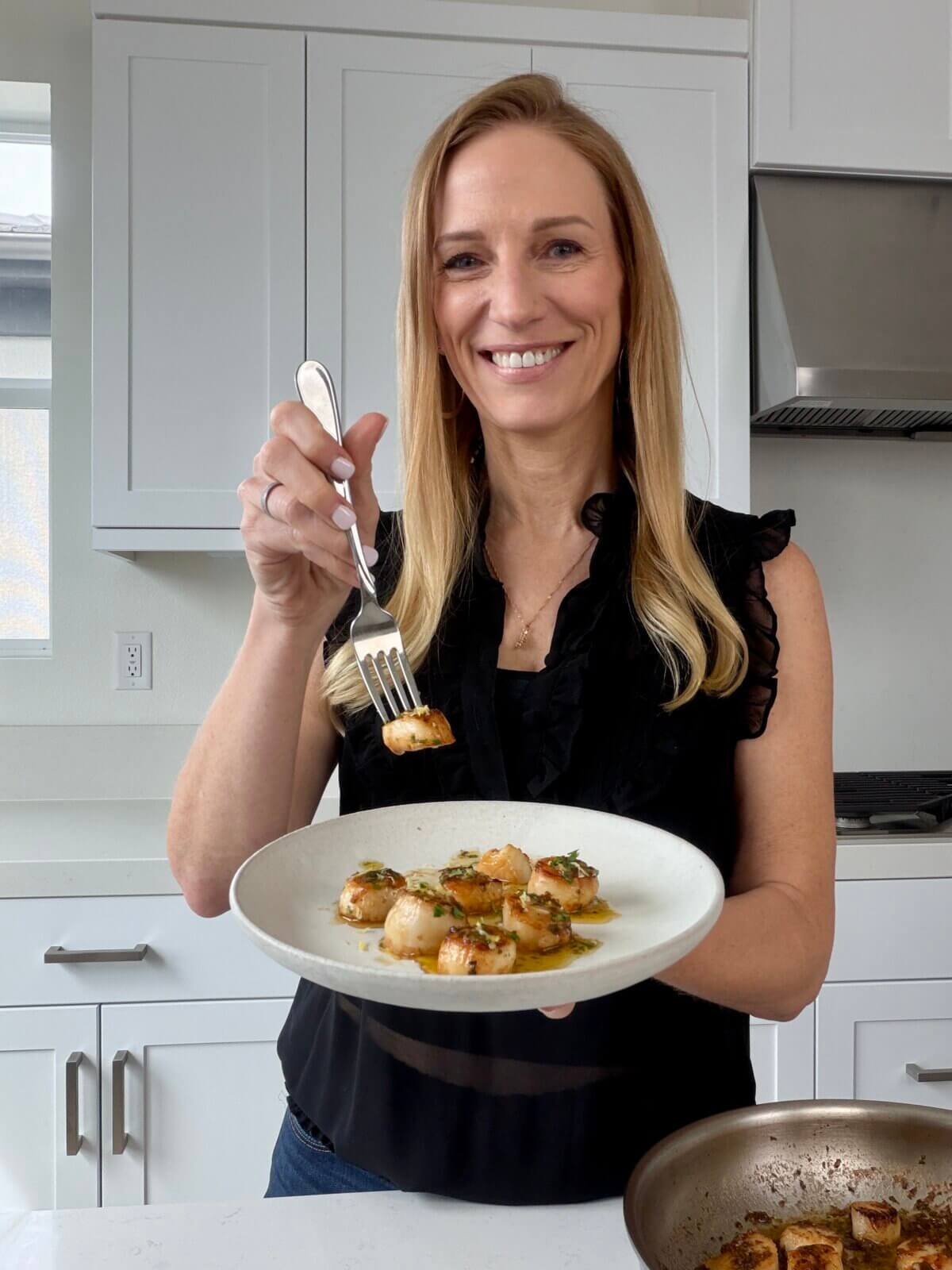 Lisa holding a plate of the scallops with lemon garlic butter sauce.