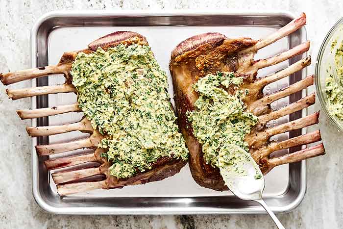 Step four of rack of lamb: spread herb butter on top.