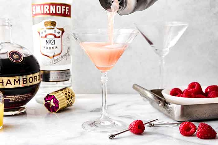 Pouring French martini into a cocktail glass.