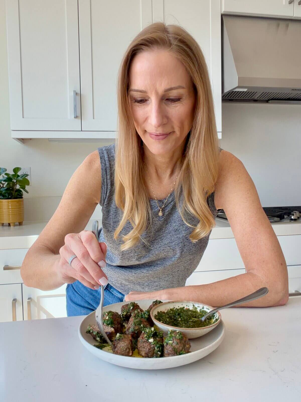 Lisa eating lamb meatballs on a plate.