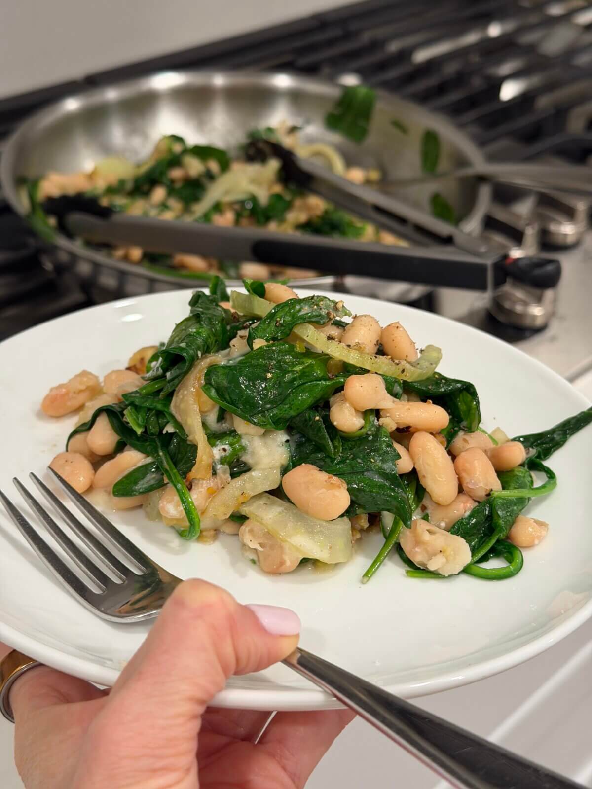 Lisa holding a plate of warm spinach and white bean salad.