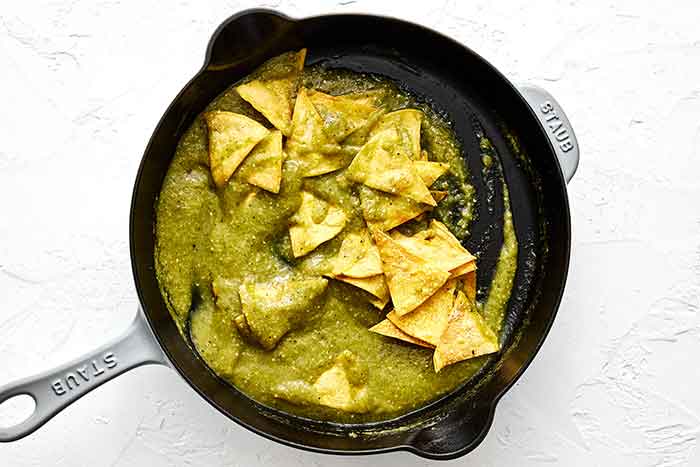 Step three chilaquiles: toss chips with salsa.