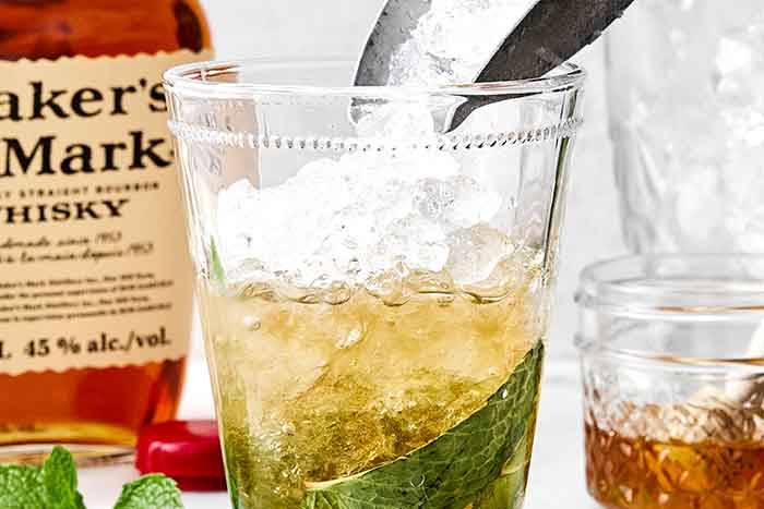 Adding pebbled ice to a mint julep cocktail.