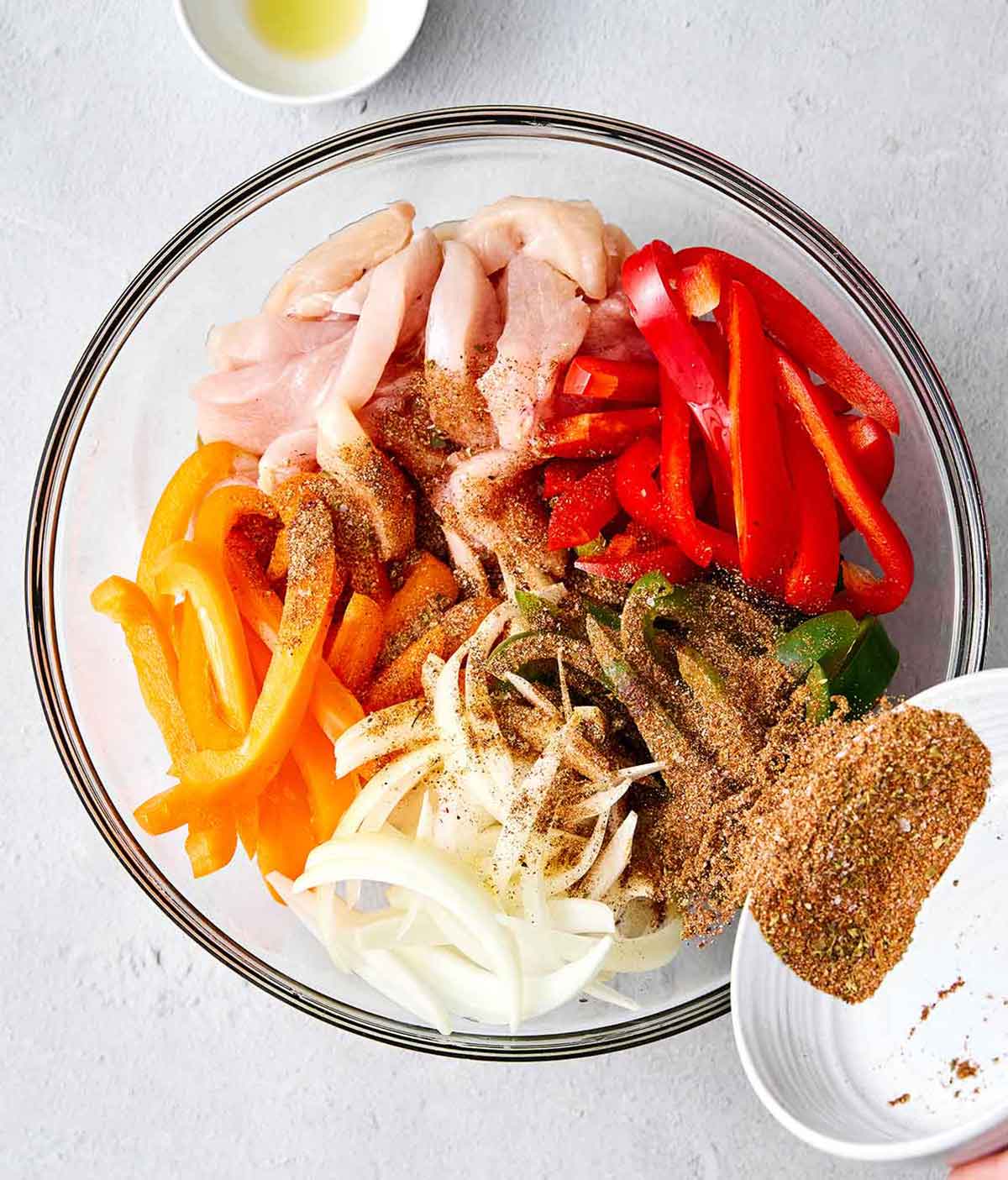 Step two of sheet pan chicken fajitas: toss everything with seasoning.