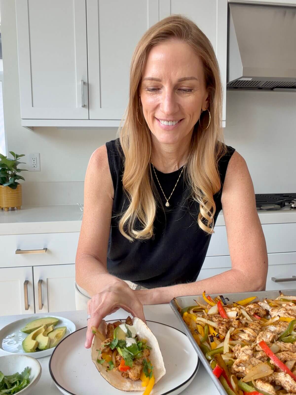 Lisa eating a plate of sheet pan chicken fajitas.