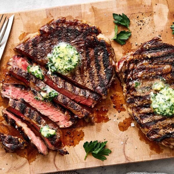 Sliced grilled ribeye steaks on a wooden board.